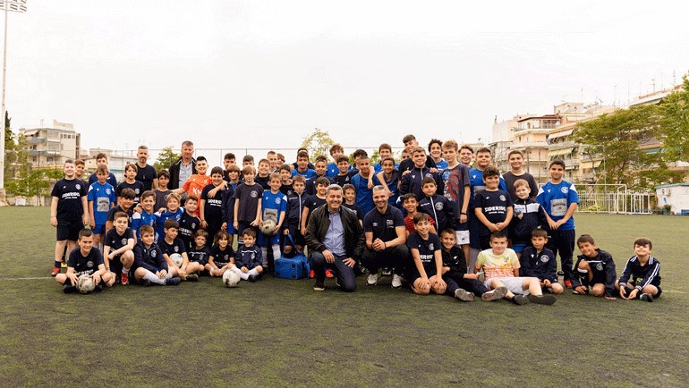 Ο Άγγελος Χαριστέας, Πρωταθλητής Ευρώπης Euro 2004, και ο Οδυσσέας Χριστοφόρου, Αναπληρωτής Διευθύνων Σύμβουλος ΟΠΑΠ, με τα παιδιά της ακαδημίας ποδοσφαίρου «Αχιλλέας Τριανδρίας»